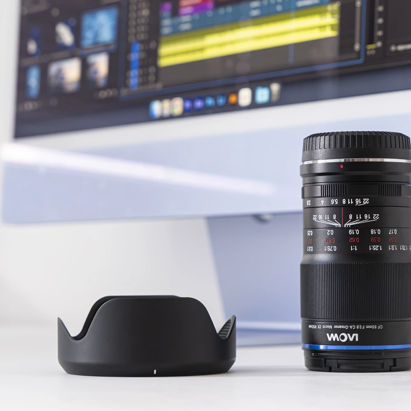 A camera lens in front of a screen displaying video editing software.